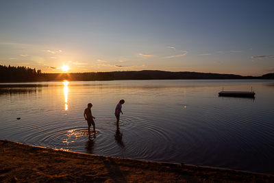 Kinderen die met blote voeten door het meer lopen met zonsondergang